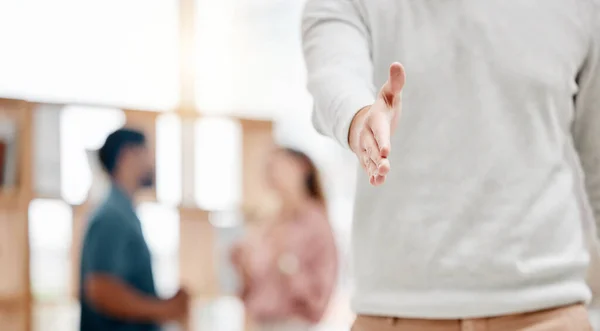 Businessperson extending their hand for a handshake in an office alone at work. One business professional giving a handshake and greeting. Employee welcoming you to the workplace.