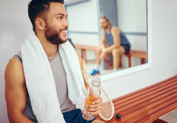 Happy friends relaxing after a match. Mixed race player drinking water after a match with his friend. Two friends talking after a squash match. Coach talking to his player in the locker room.