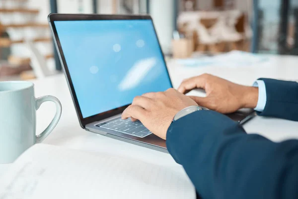 Closeup of a mixed race businessman typing an email on a laptop alone at work. One hispanic male businessperson working on a laptop in an office at work.