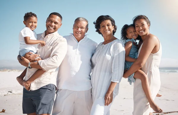 Portrait of smiling mixed race family with little boy and girl standing together on a beach. Adorable little son and daughter bonding with mother, father, grandmother and grandfather over a weekend.