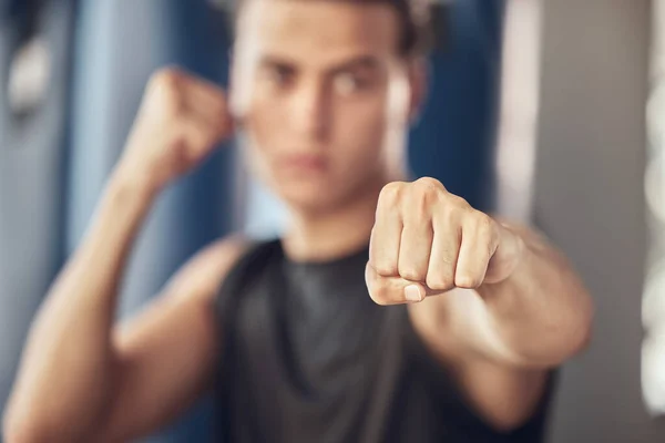 Closeup on the hand of an athlete. Boxer punching in the gym. Strong bodybuilder boxing in the gym. Active fit man throwing a punch in the gym. Strong boxer training in the gym.