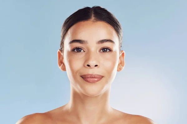 Closeup face beautiful young mixed race woman. An attractive female posing in studio isolated against a blue background. A skincare regime that keeps your skin soft, smooth, glowing and healthy.