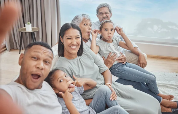 Happy and affectionate young mixed race family of six taking a selfie at home. Married couple with their mother, father, son and daughter in the lounge. Taking a photograph with with grandparents.