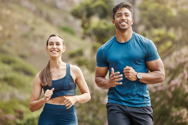 Fit young man and woman running together outdoors. Interracial couple and motivated athletes doing cardio workout while exercising for better health and fitness at the park.