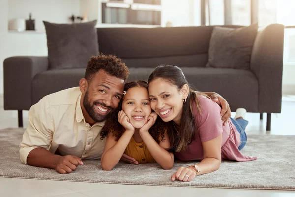 Portrait of mixed race parents enjoying weekend with cute daughter in home living room. Smiling hispanic girl bonding with mother and father in lounge. Happy couple lying together with kid on weekend.