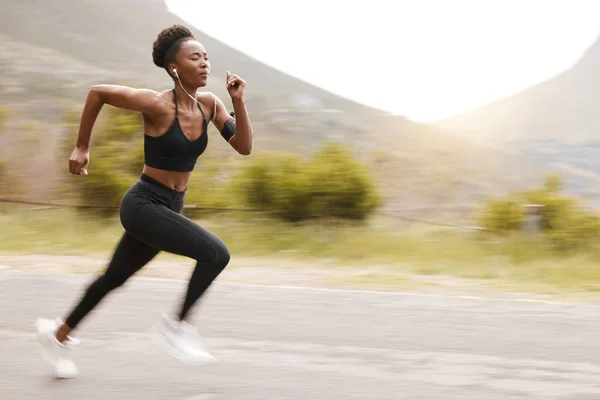 One african american female athlete looking focused while out for run to increase her cardio and endurance. A young black woman running outside to increase her speed and pace. Fitness is a lifestyle.