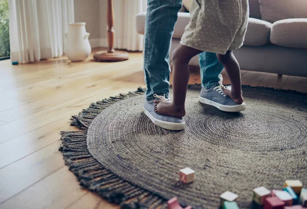 an unrecognizable parent and child dancing together at home.