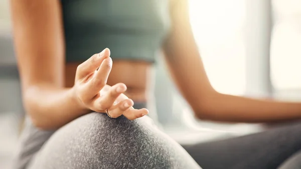 a young woman meditating in her living room.