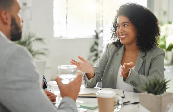 Businesspeople talking in a meeting together at work. Business professionals talking and planning in an office. Young mixed race businesswoman with a curly afro explaining an idea to colleagues at a