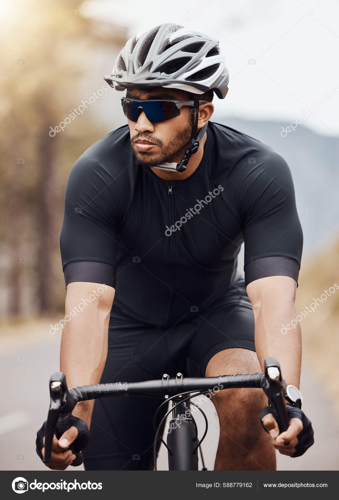 Hombre joven guapo con casco y gafas de sol en una bicicleta