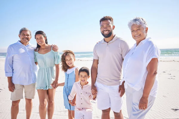 Portrait of multi generation family standing together at the beach together. Mixed race family with two children, two parents and grandparents spending time together by the sea.