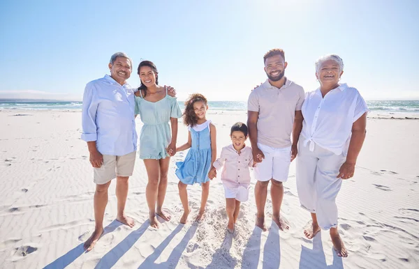 Multi generation family standing together at the beach. Mixed race family with two children, two parents and grandparents spending time together by the sea.