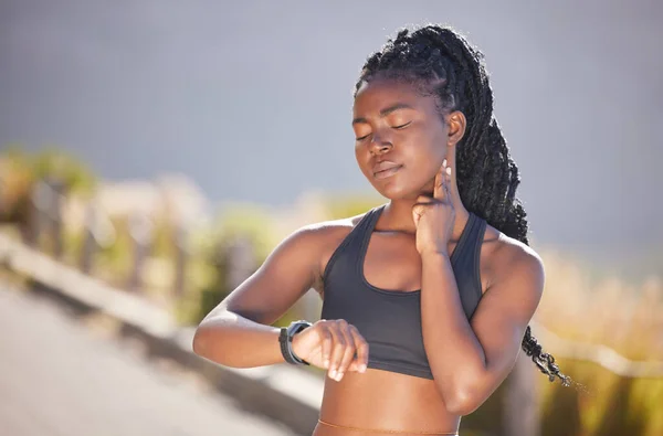 One beautiful young african american woman checking her pulse while exercising outdoors. A fit and sporty female athlete checking her heart rate on a smart watch during a workout. Counting the beats.