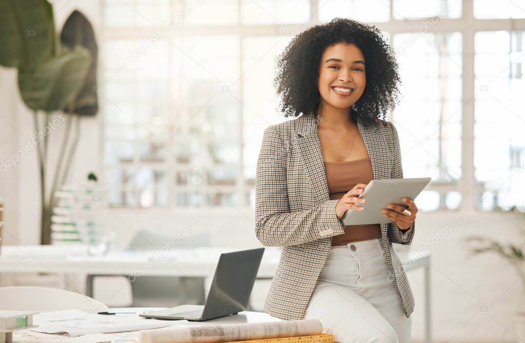 Happy businesswoman using a digital tablet. Young leading businesswoman using a wireless tablet. Creative designer working in her agency. Designer standing in her office using an online app.