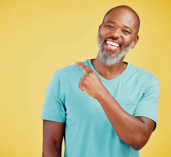 Mature African Man Laughing Pointing Direction Yellow Studio Background Black — Zdjęcie stockowe