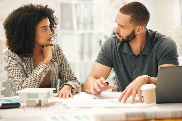 Focused colleagues working on a project together. Young architects working together in an office. Businesspeople working in a design agency. Professional creatives brainstorm and collaborate