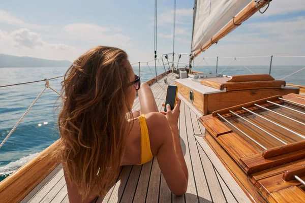 Young Woman Yellow Swimsuit Sunbathing Boat Deck Using Her Cellphone — Stock fotografie
