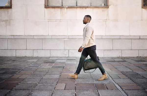 Black businessman travelling alone.A african american businessman walking around town with his luggage while looking stylish in the city.