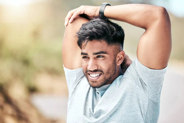 Fit young mixed race man stretching before his exercise outdoors. Handsome hispanic male warming up and getting ready in preparation for a run or jog outside in nature. Endurance and cardio training.