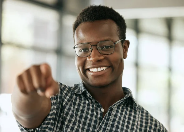 Portrait of a confident young professional african american business man with glasses pointing index finger at camera while standing in an office. HR manager choosing you.
