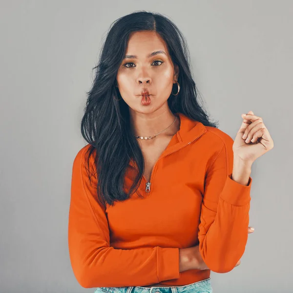 Portrait of mixed race woman isolated against grey studio background with copyspace and pouting. Beautiful young hispanic standing alone and making silly and goofy facial expression. One model posing.