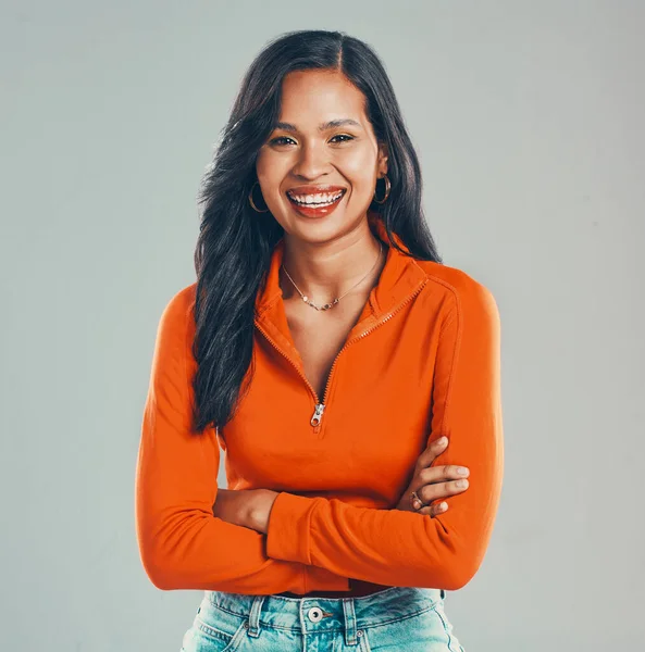 Portrait of smiling mixed race woman isolated on grey studio background with copyspace with arms crossed. Beautiful happy young hispanic standing alone with arms folded. One model feeling confident.