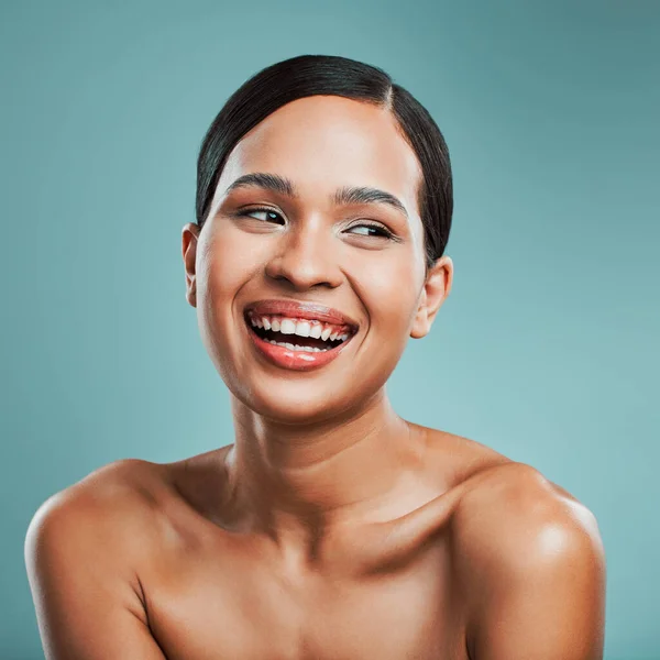 A young beautiful mixed race woman with smooth soft skin posing and smiling against a green studio background. Attractive Hispanic female with stylish makeup posing in studio.