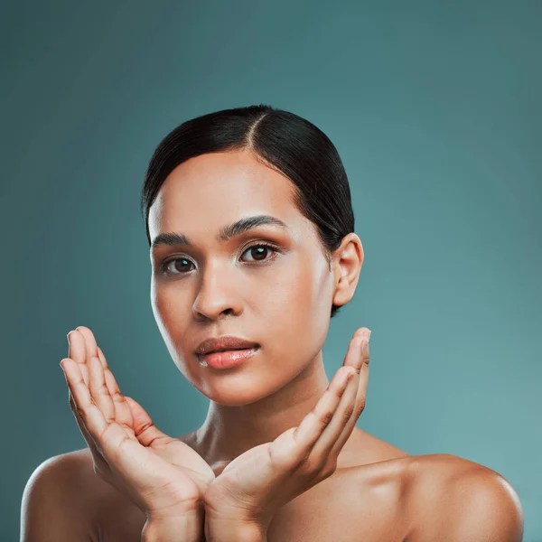 Portrait of a young beautiful mixed race woman with smooth soft skin posing against a green studio background. Attractive Hispanic female with stylish makeup posing in studio.