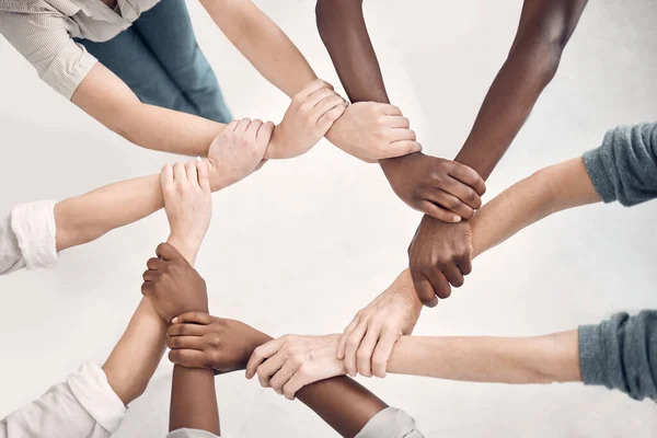 Businesspeople gripping and holding each others wrists in an office at work. Business professionals joining their arms and holding wrists in support. Colleagues huddling and staying connected by