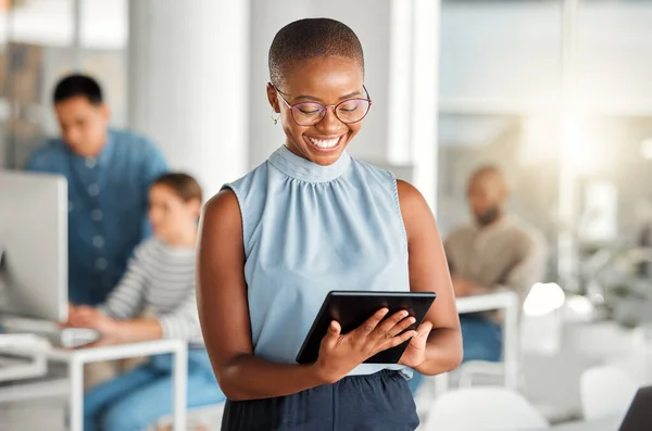 Cheerful african american businesswoman working on a digital tablet at work. Joyful black female businessperson using social media on a digital tablet. Businessperson checking an email on a digital