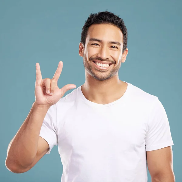 Handsome Young Mixed Race Man Gesturing Rock While Standing Studio — стокове фото