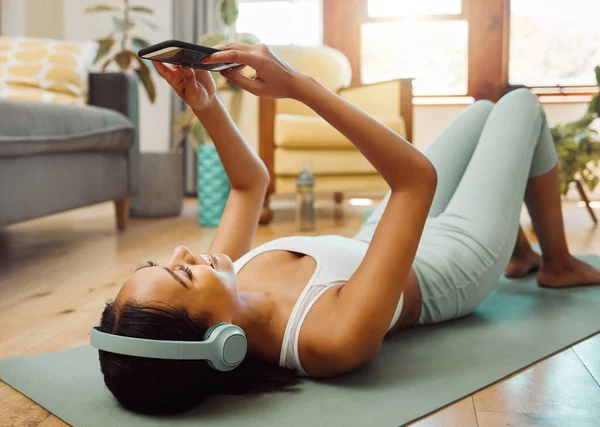 Sporty Young Woman Wearing Headphones Using Cellphone While Exercising Home — ストック写真