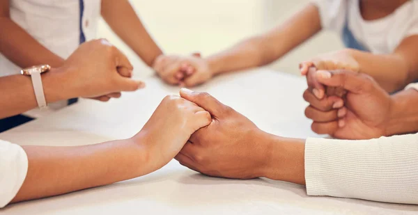 Close up of couple holding hands and praying with their kids at table. Parents and children saying prayer and worship together. Having hope and faith, World day of prayer.