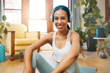 Portrait of a sporty young woman wearing headphones while exercising at home.