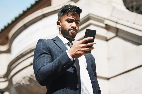a handsome young businessman sending a text message while out in the city.