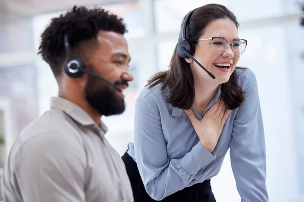 Cheerful caucasian call centre telemarketing agent training new mixed race assistant on in an office. happy supervisor troubleshooting solution with intern for customer service and sales support. Two