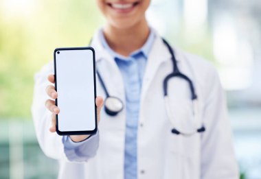Tanımlanamayan bir doktorun hastanede elinde boş bir ekranla cep telefonu tutarken çekilmiş yakın plan fotoğrafı..