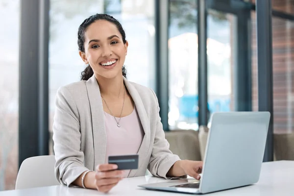 Businesswoman shopping online with her credit card. Entrepreneur paying bills using a debit card. Happy businesswoman making ecommerce purchase with her card. Woman banking online with her debit card.