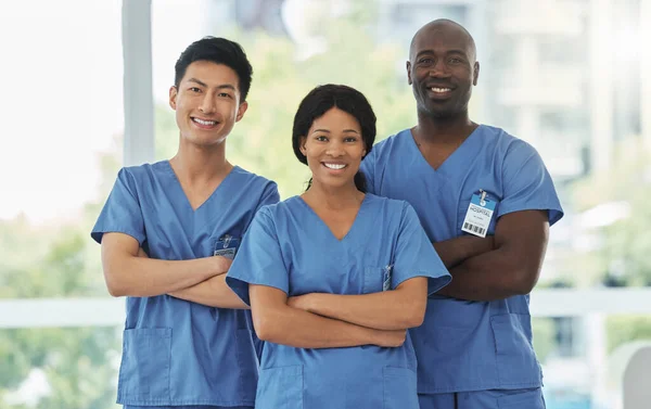 Portrait of a group of medical practitioners standing together with their arms crossed in a hospital.