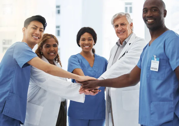 Portrait of a group of medical practitioners joining their hands together in a huddle in a hospital.
