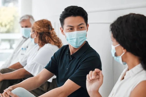 a group of people wearing face masks while sitting in a queue.