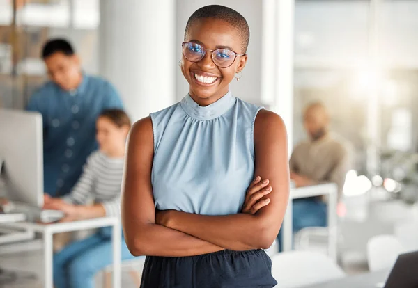 Young happy african american businesswoman standing with her arms crossed while in an office. Confident and content black woman boss smiling and standing at work.