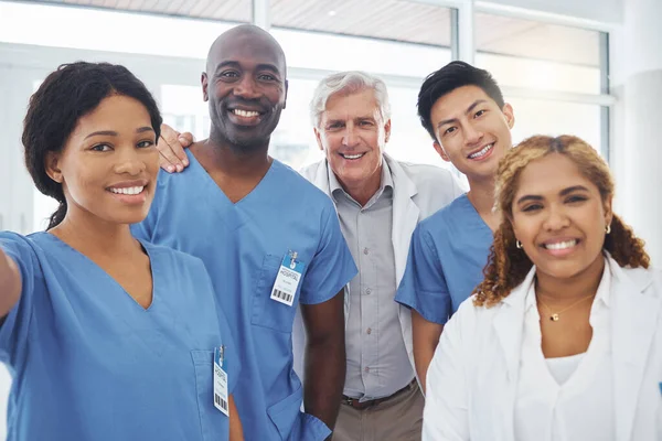 Portrait of a group of medical practitioners taking selfies together in a hospital.