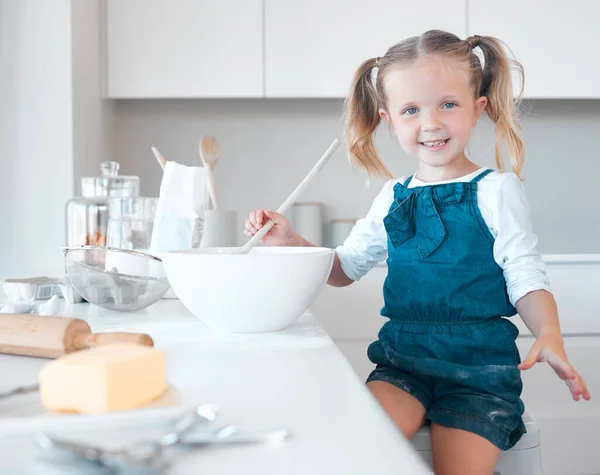 Happy little girl baking alone. Caucasian child baking in her kitchen. Portrait of a young girl mixing a bowl of batter. Little girl enjoying baking at home. Smiling child baking