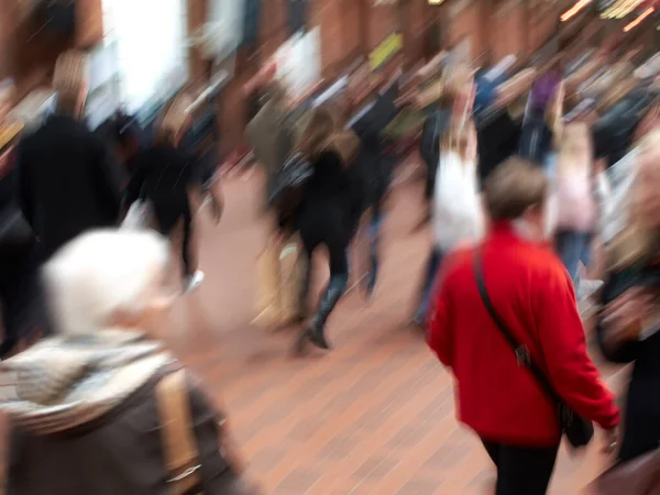 A group of people commuting through urban roads with blurred motion. A busy crowd of travelers arriving and walking together in a street in the city. Lots of tourists in defocused movement downtown.