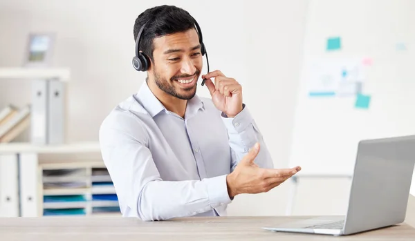 Businessman working in a call center. Customer service agent talking to a customer. Sales rep wearing a headset using a laptop. IT assistant giving advice. Call center worker using his computer.