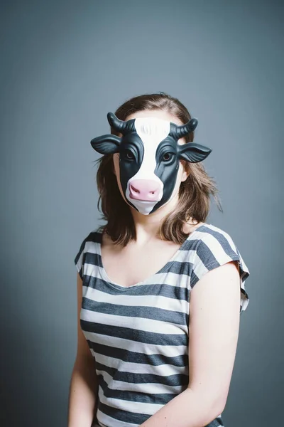 Young woman wearing mask against a grey background in studio.