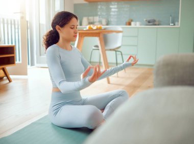 Beautiful young mixed race woman meditating in the asana position while practicing yoga at home. Hispanic female exercising her body and mind, finding inner peace, balance and clarity.
