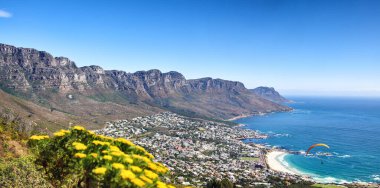Landscape of a mountain range near a coastal city against a blue horizon in summer, South African. Wide angle wallpaper of The twelve apostles near calm sea and popular travel location for copy space. clipart
