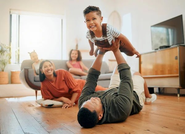 A happy mixed race family of five relaxing in the lounge and being playful together. Loving black family bonding with their son while playing fun games on the floor at home.